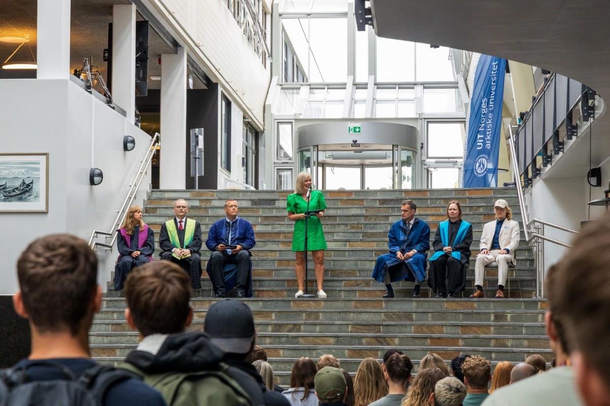 250811 Studiestart i Narvik foto Vilde Øines Nybakken (13).jpg en kvinne i grønn kjole står i en trapp og taler til en gruppe mennesker